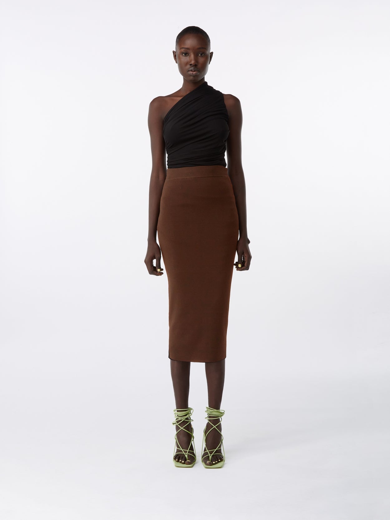 model wearing a black one shoulder draped jersey bodysuit and a brown midi knit pencil skirt