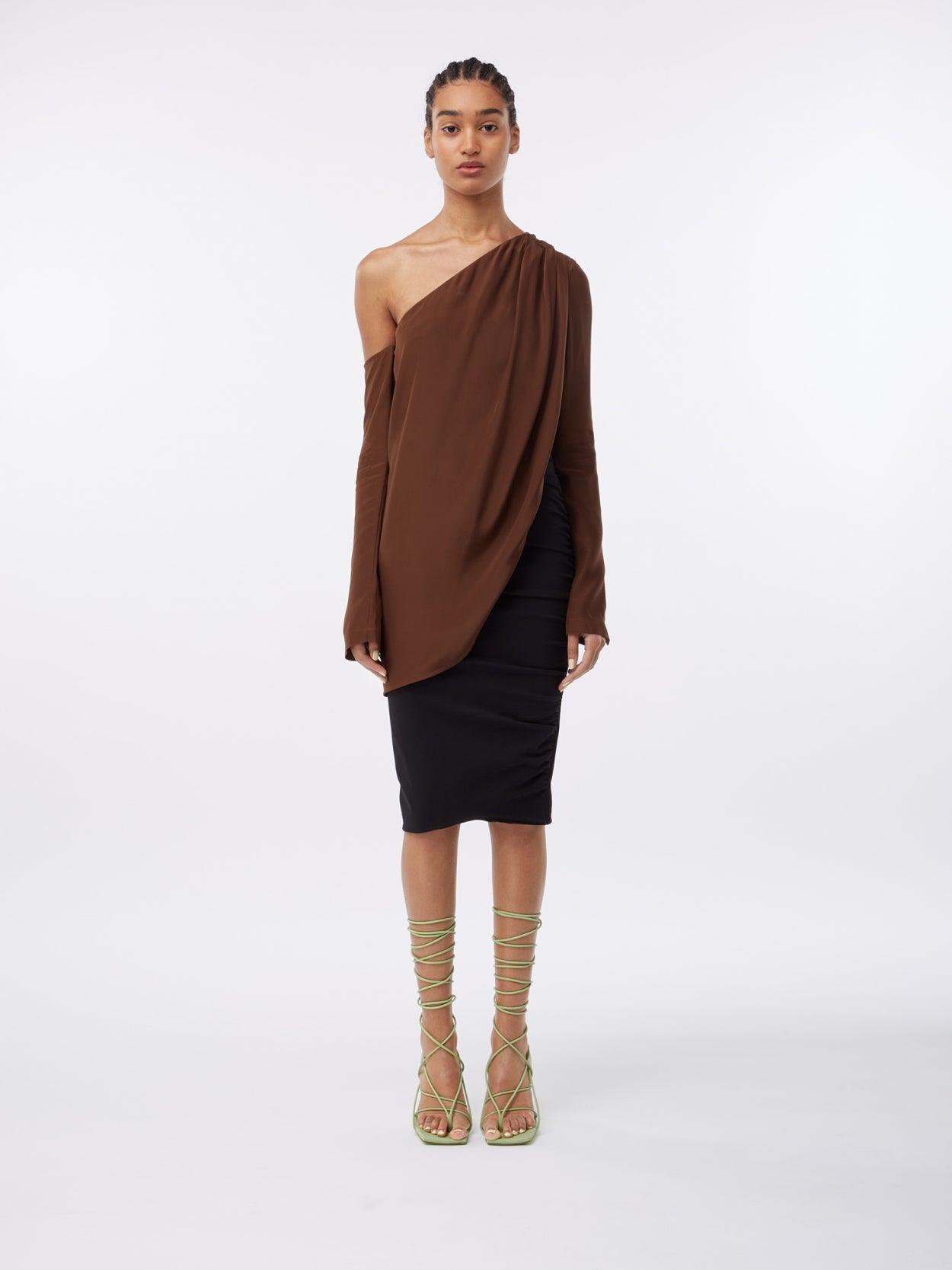 model wearing a brown asymmetric long sleeve silk top and a black midi pencil skirt with waist strap