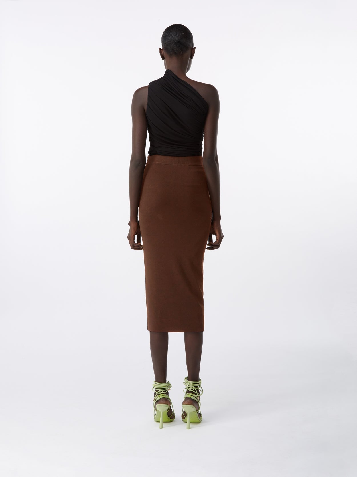model wearing a black one shoulder draped jersey bodysuit and a brown midi knit pencil skirt