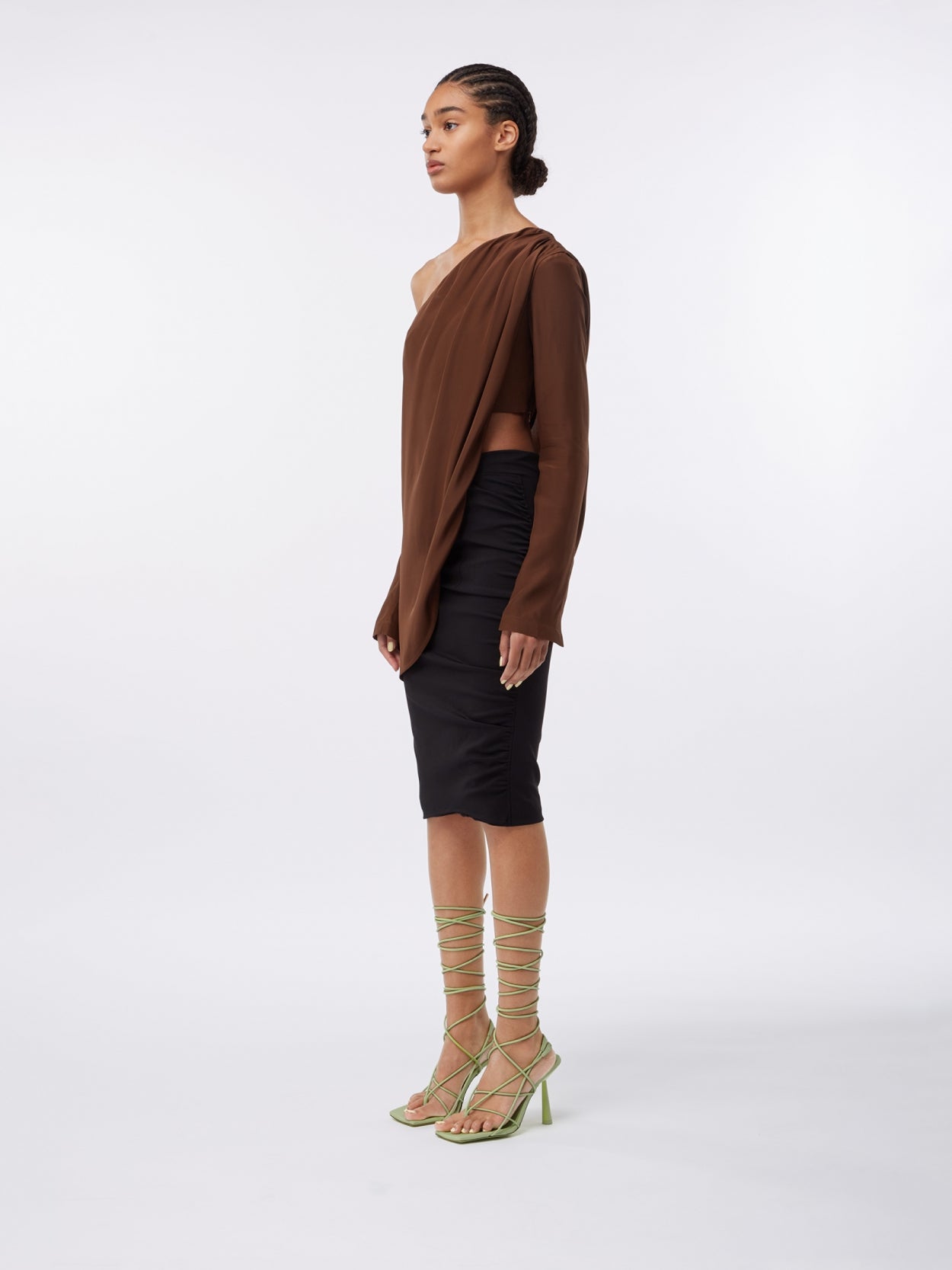 model wearing a brown asymmetric long sleeve silk top and a black midi pencil skirt with waist strap